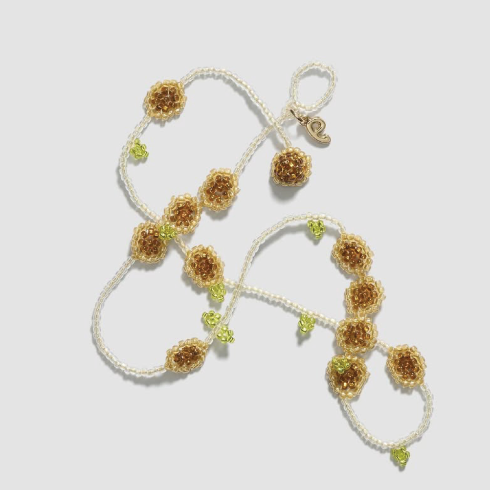 A delicate necklace made of clear glass beads, featuring small, intricately woven sunflower charms with brown centers and green leaf accents.